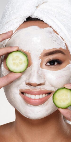 attractive-smiling-lady-with-scrab-face-holding-cucumber-slices